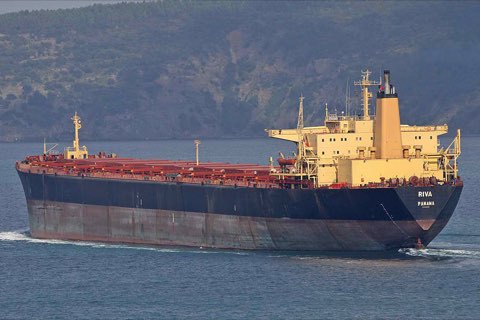 A large bulk carrier with a black hull and yellow superstructure underway at sea.