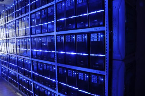 Rows of server racks with blue lights in a data center aisle.